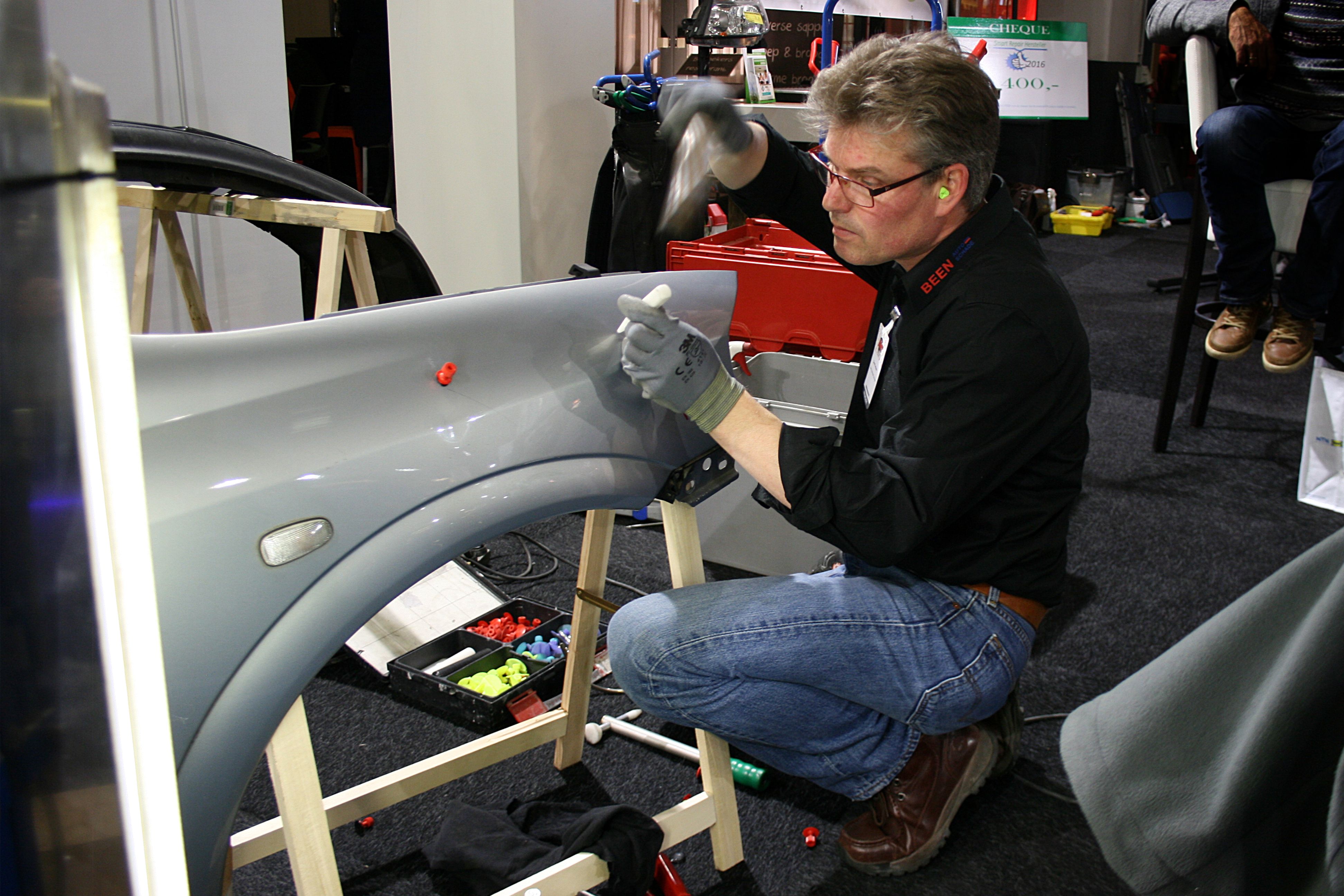 Bernd Terhoeve van Been Autoschade Groningen (met oordopjes in, dat zag de jury graag) werkt geconcentreerd aan de schades op het Opel-spatbord.