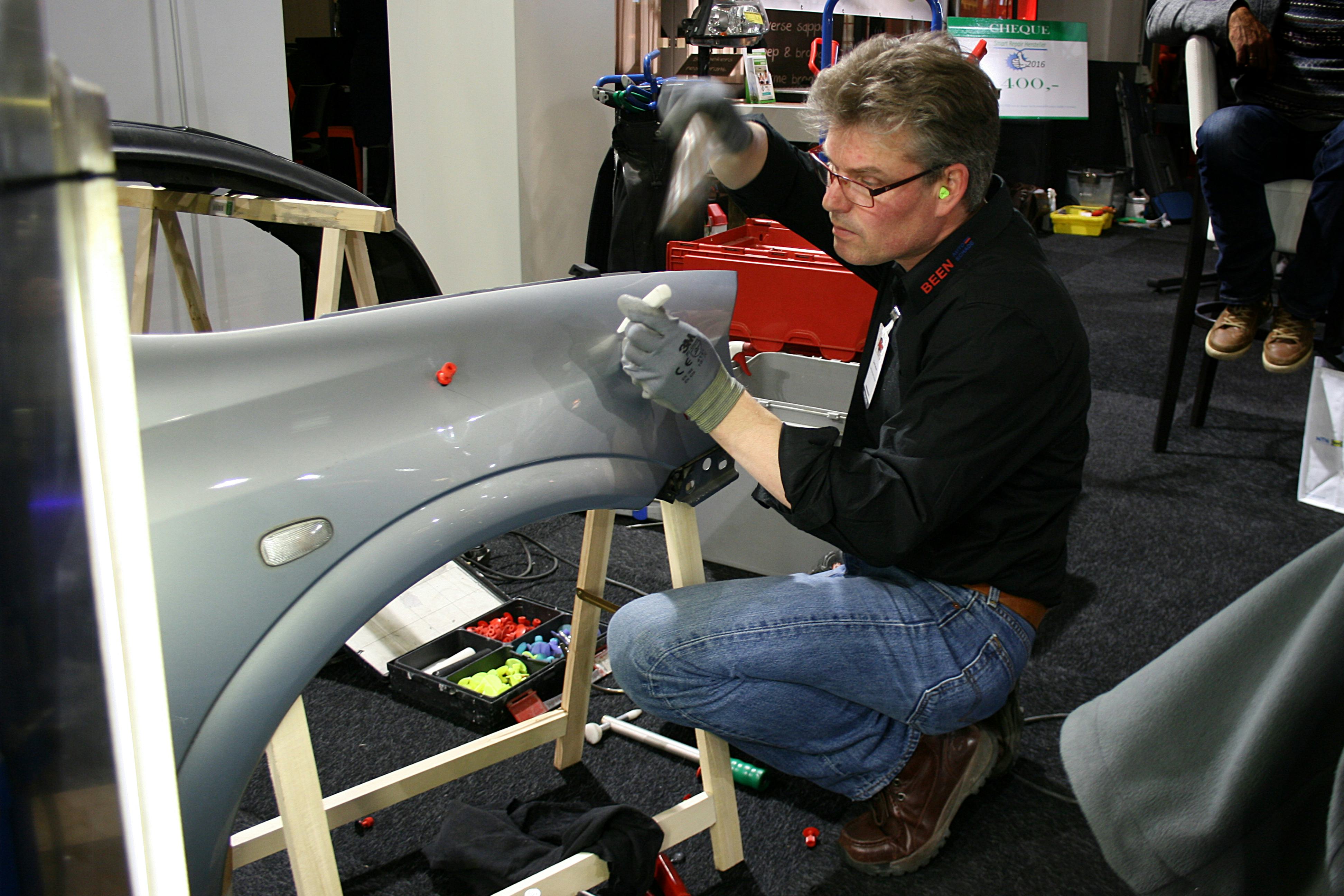 Bernd Terhoeve van Been Autoschade Groningen (met oordopjes in, dat zag de jury graag) werkt geconcentreerd aan de schades op het Opel-spatbord.