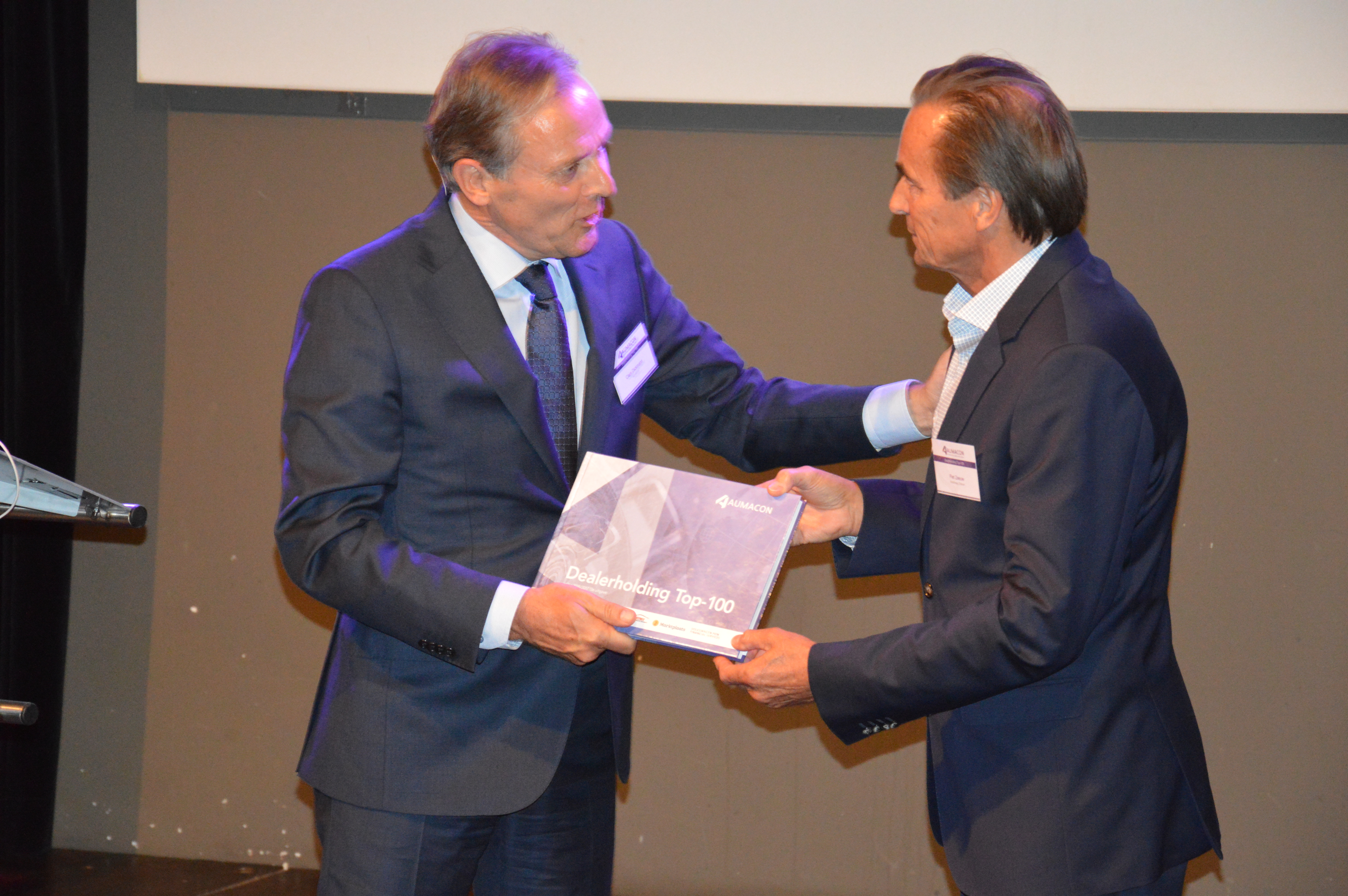 Directeur Piet Zeeuw van runner-up Autohaag Zeeuw ontvangt het eerste exemplaar van de vuistdikke Dealerholding Top 100 uit handen van Aumacon-directeur Clem Dickmann.