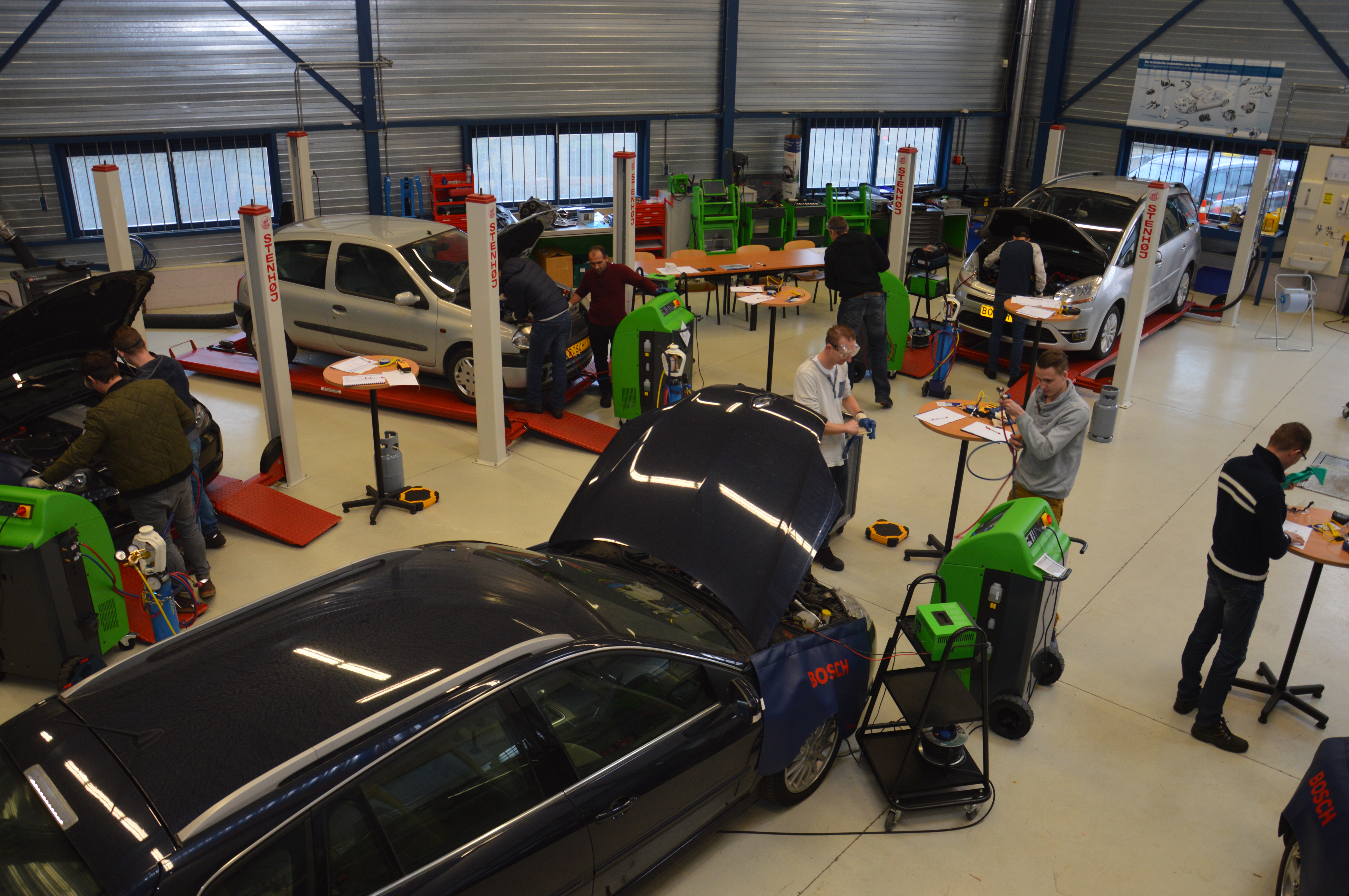 Echt leren doe je door te doen. De twaalf cursisten gaan in groepjes van twee aan de slag met een auto en aircoserviceapparatuur.