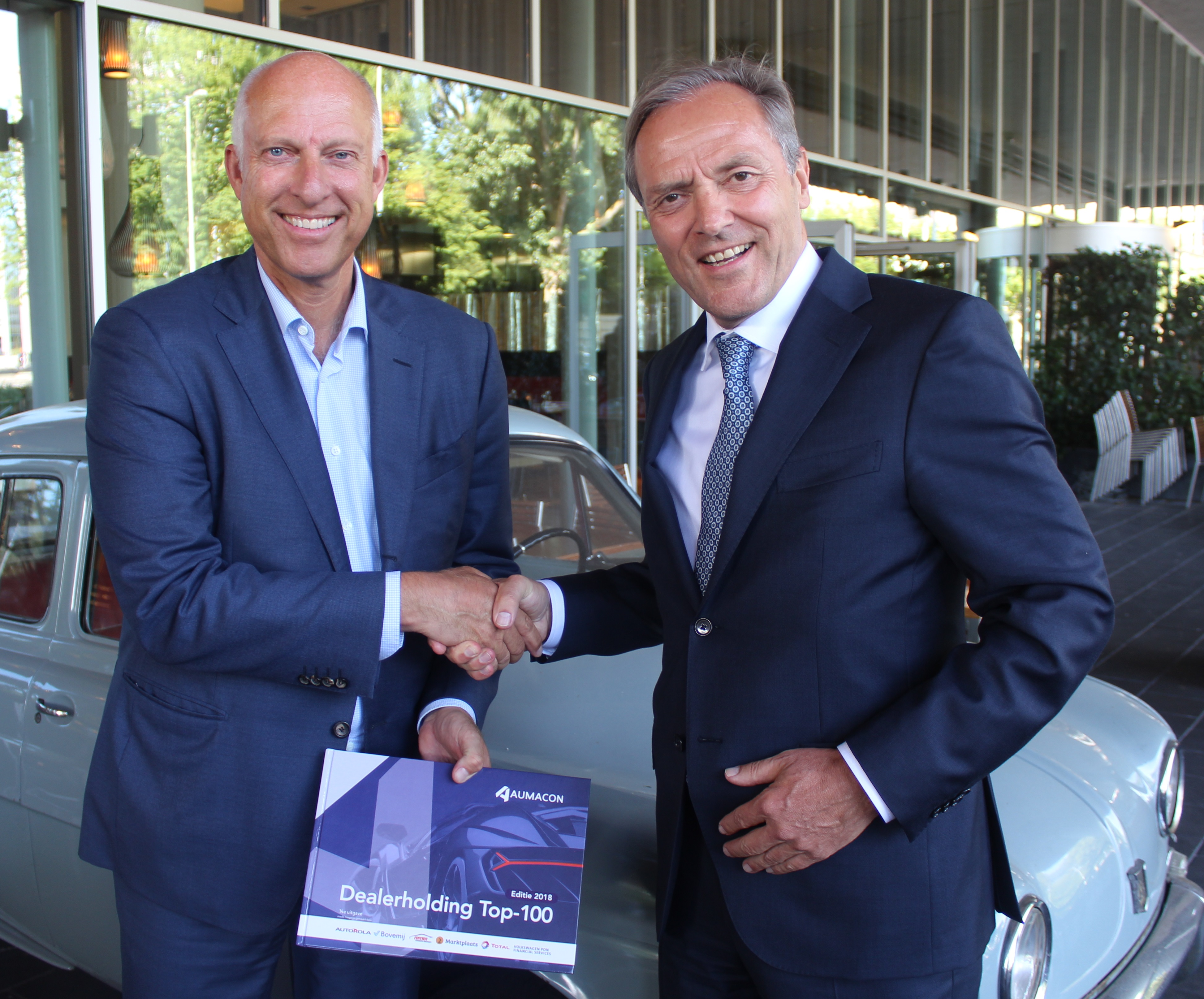 Clem Dickmann overhandigt het allereerste exemplaar van de AUMACON Dealerholding Top-100 Editie 2018 aan Mark van der Kallen (links), dga van Riva Holding. 