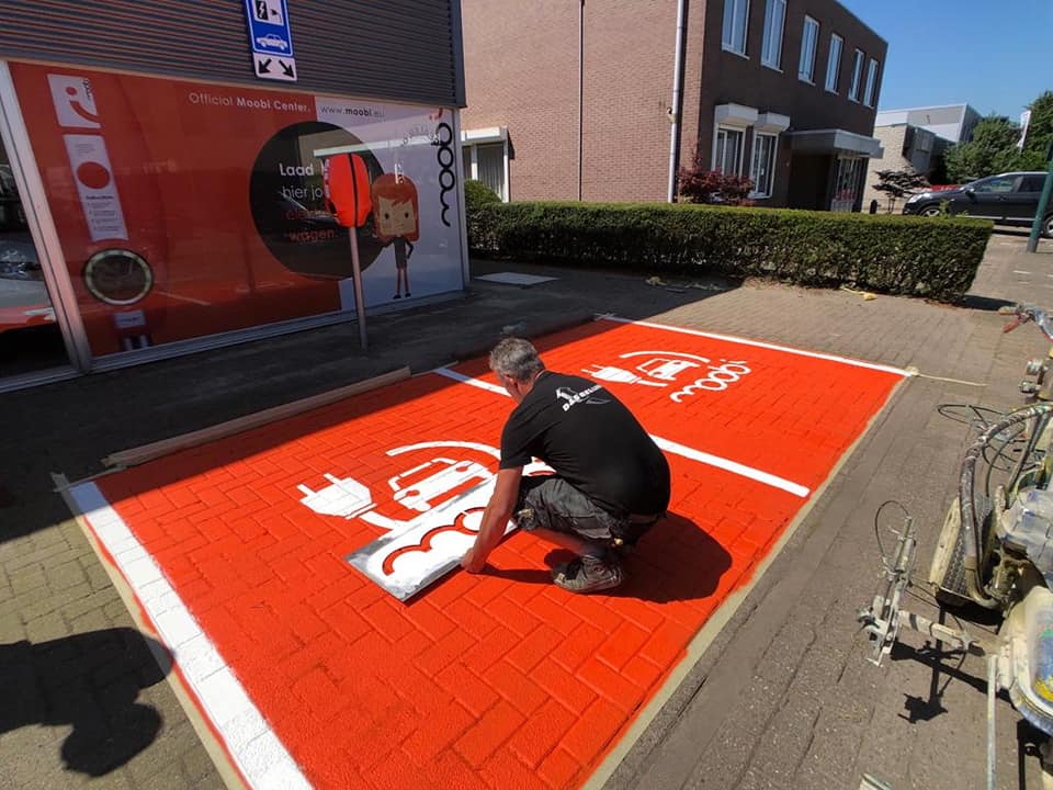 Een laadpaal en feloranje parkeervakken markeren het Moobi Center.