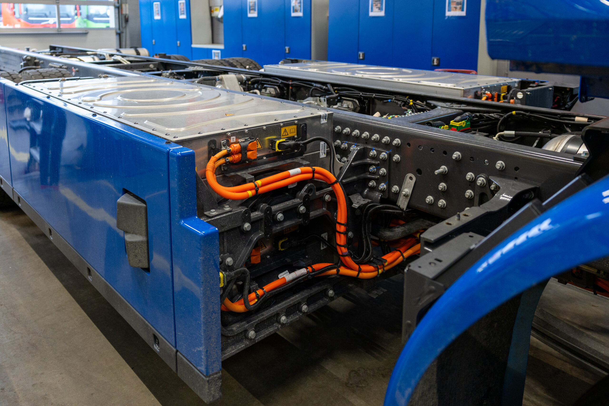 De werkplaats in Aalsmeer bestaat uit drie afdelingen: de hoofdwerkplaats, de apk-teststraat en de nieuwbouwhal. Van elektrische trucks kijkt niemand nog op. De nieuwbouwwerkplaats staat vol met nieuwe e-trucks die worden voorbereid voor opbouw en ombouw. Veilig werken is prioriteit nummer een, benadrukt Ricky. “Er zijn geen foutmarges bij elektrische trucks. Je moet altijd de voorgeschreven werkprocedures volgen en de juiste pbm’s gebruiken. Veiligheid voor alles.”