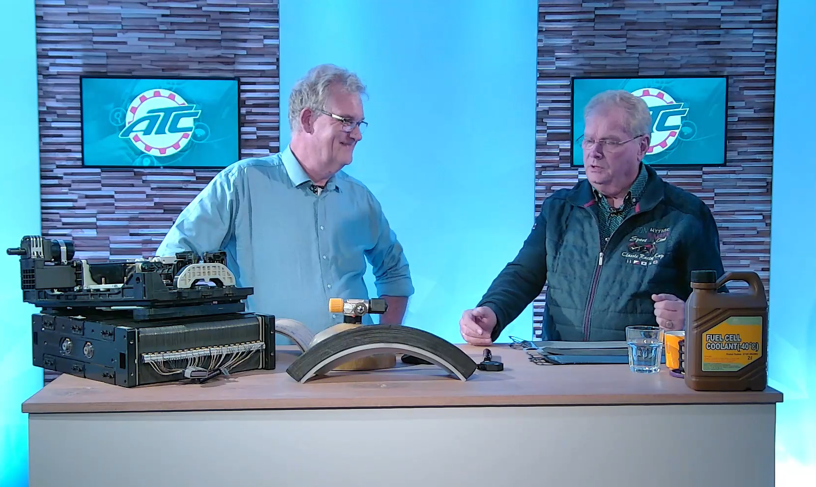 Adriaan van Broekhoven (links) bracht de nodige demo-stukken mee, zoals een brandstofcelstack, een hogedruk tank doorsnede, rechts de noodzakelijke koelvloeistof van 20 euro per liter.