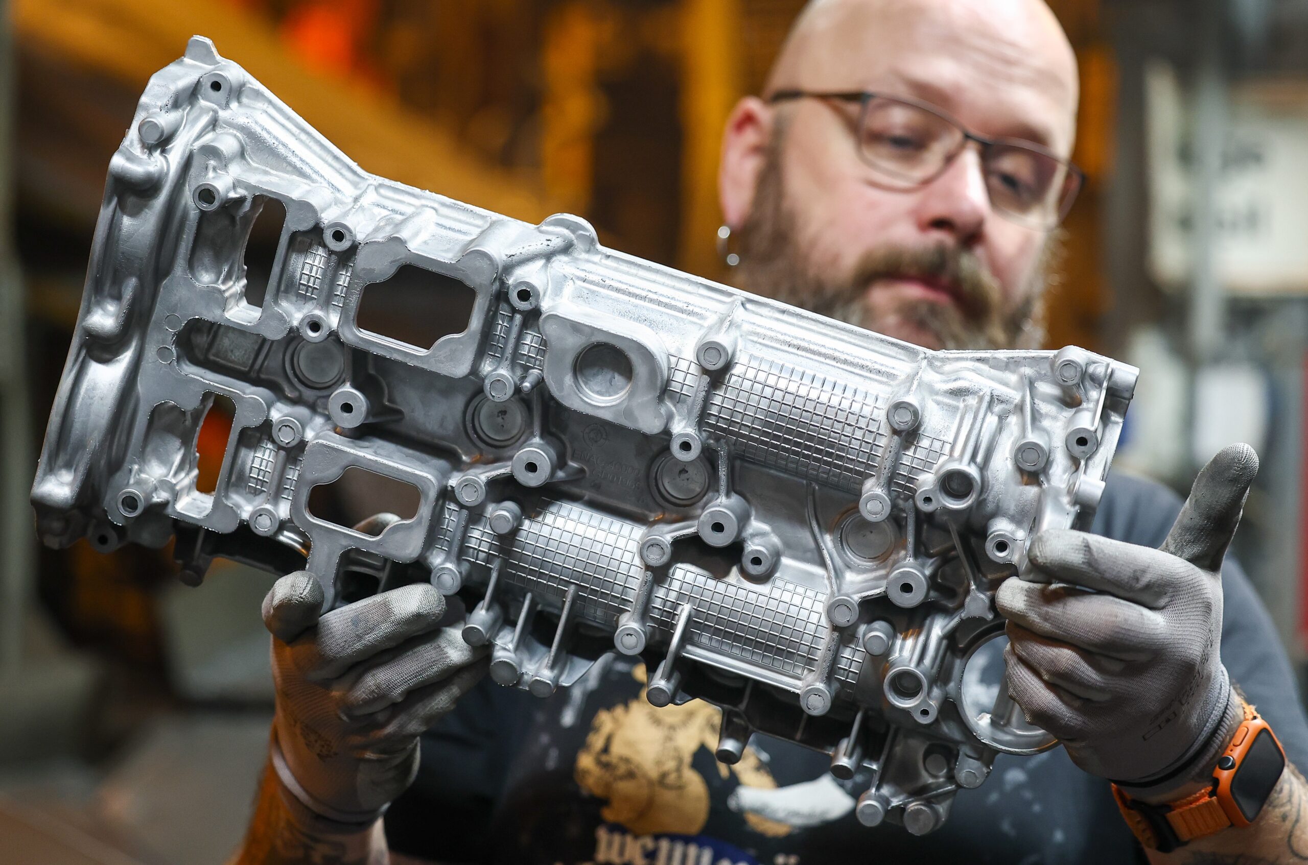 Een medewerker van Handtmann Leichtmetallgießerei Annaberg GmbH, een toeleverancier van Europese autofabrikanten, inspecteert een aluminium gietstuk na het gieten. - Foto: Jan Woitas/dpa